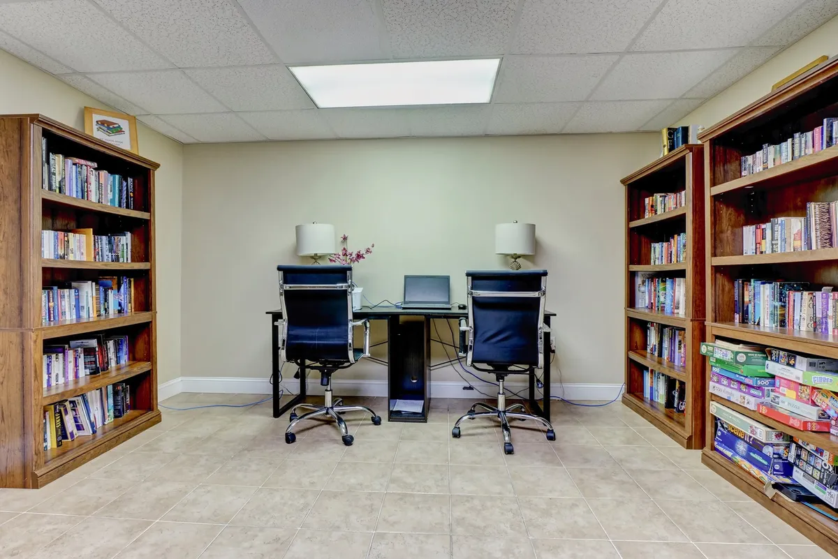 This interior scene features bookshelves filled with books, desks with chairs, and desk lamps, creating a calm, productive atmosphere. The space is tailored for reading, studying, working, or collaborating, reflecting the business-friendly amenities for remote workers.