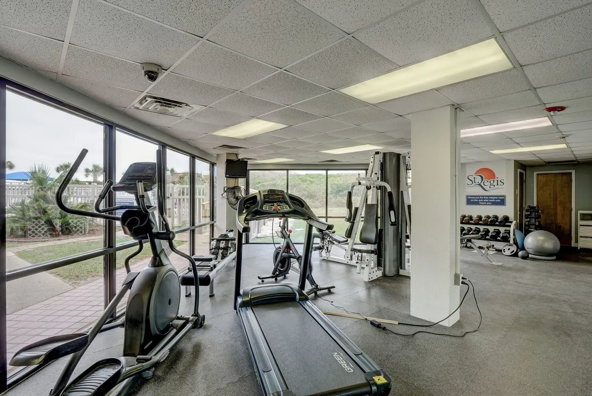 A bright and inviting fitness center filled with treadmills, elliptical machines, weight equipment, and large windows letting in natural light. The setup is modern and motivational, encouraging guests’ wellness routines.
